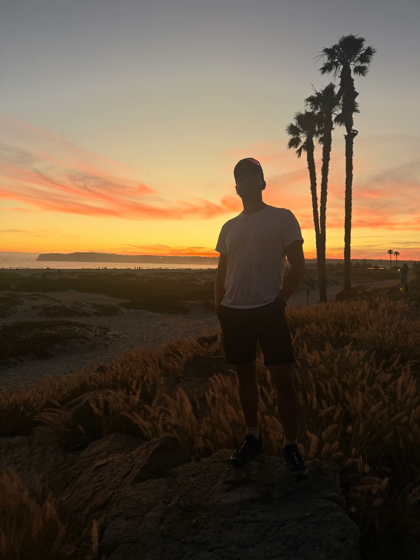 Özgün Barış Kır standing on a coastal bluff at sunset